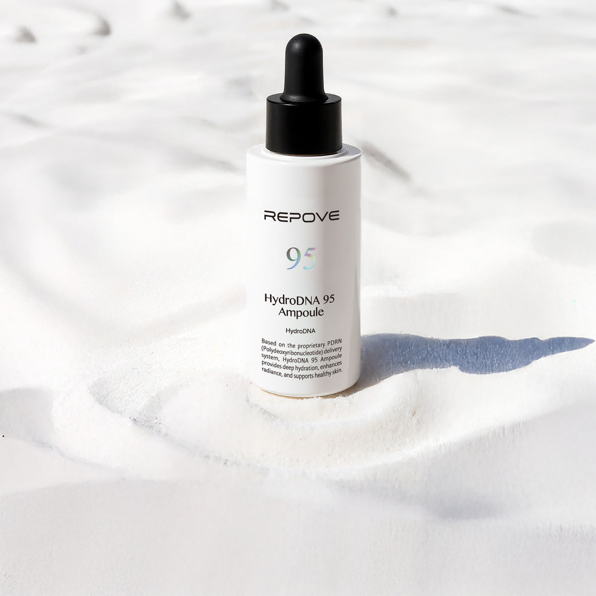 Flacon REPOVE HydroDNA 95 Ampoule posé sur du sable blanc